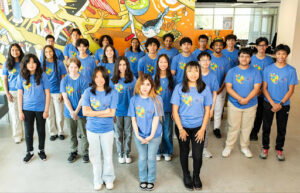a group of students in blue T-shirts in front of a mural