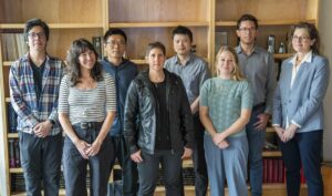 a group of 8 people in front of bookshelf background